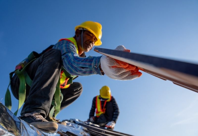 Close up hand of worker install new ceramic tile roof in the co Close up hand of worker install new ceramic tile roof in the construction site.